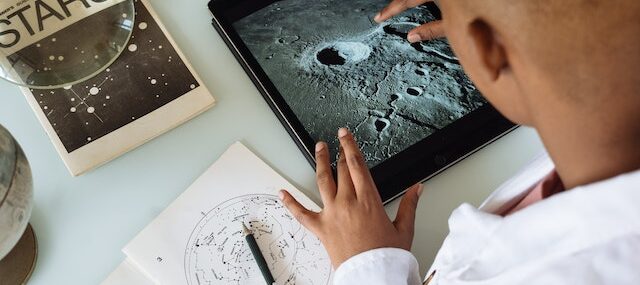 Ученый разглядывает лунный кратер на планшете